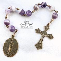 This is a one decade Catholic pocket rosary featuring Stella Maris, Our Lady Star of the Sea.  The chaplet is made up of 10 beads of 8mm Chevron Amethyst.  Natural and semi-precious beads will often have slight variations in shape and other inclusions, which lends to each stone's uniqueness and beauty.  At one end there is a solid bronze crucifix; the other end has an antique cast medal in solid bronze featuring Stella Maris.  This can be made using sterling silver parts for an additional charge Handmade Adjustable Purple Rosary, Handmade Spiritual Purple Rosary Bracelet, Star Of The Sea, Pocket Rosary, Stella Maris, Chevron Amethyst, Precious Beads, Rosary Catholic, Semi Precious Beads