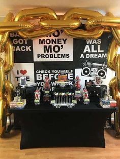 a black table topped with gold balloons and lots of other items in front of a sign that says money mo?