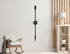 a black and gold clock on the wall in a living room with a rocking chair