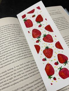 a bookmark with strawberries on it is laying open to show the inside pages