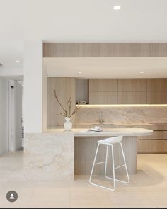 a modern kitchen with marble counter tops and white stools