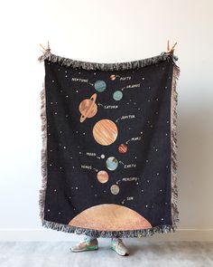 a woman standing in front of a black blanket with planets on it