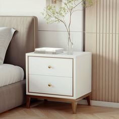 a white nightstand sitting next to a bed with a plant in it on top of it