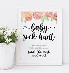 a baby sock hunt sign next to a potted plant with white flowers in it