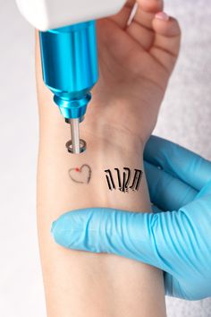 a person with blue gloves on their arm is using a machine to tattoo the wrist