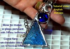 a hand holding a blue glass pendant with words describing how to make an origami triangle