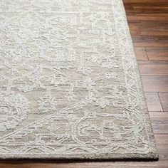 a beige rug with an intricate design on the top and bottom, sitting on a wooden floor