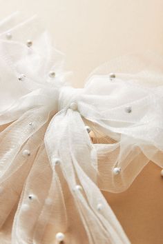 the back of a white dress with pearls and tulle on it's waist