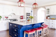 a kitchen with white cabinets and blue island