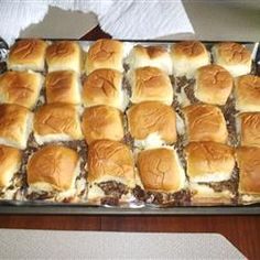 a pan filled with sliders sitting on top of a wooden table