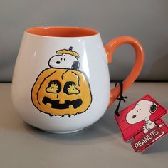 a snoopy pumpkin mug with peanuts on it