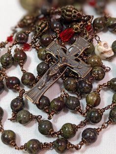 I made this stunning rosary using 6mm dragons Blood jasper for the Ave beads that are double capped in bronze and each bead is wire-wrapped for strength and durability.  I used a pumpkin style vintage 8mm brass bead for my Pater beads that I double capped with filigree caps in which I put a small red Swarovski crystal bead that will sparkle in the light.  I make my own spacer beads,  for this rosary I used a red 3mm Swarovski crystal bicone bead w/two brass beads at either end, by using the red Spiritual Wire Wrapped Crucifix Jewelry, Handmade Bronze Crucifix Jewelry, Handmade Bronze Spiritual Rosary, Handmade Spiritual Bronze Rosary, Handmade Bronze Rosary As A Gift, Antique Handmade Rosary As Gift, Handmade Spiritual Rosary With Cross, Handmade Spiritual Rosary With Crucifix, Rugged Rosary