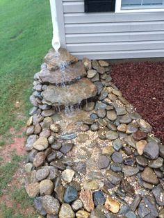 there is a small waterfall in the middle of this rock garden bed that has rocks on it