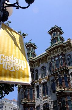 a sign hanging from the side of a light pole in front of a large building