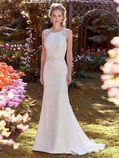 a woman standing in front of flowers wearing a wedding dress