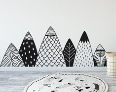 a black and white wall decal with an abstract forest scene in the background, along with a round rug