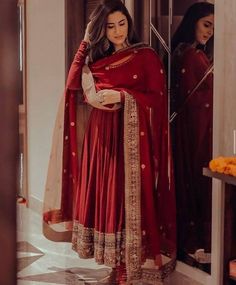 a woman in a red and gold outfit standing next to a mirror with her hands on her head