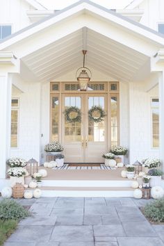 a white house with two front doors and wreaths