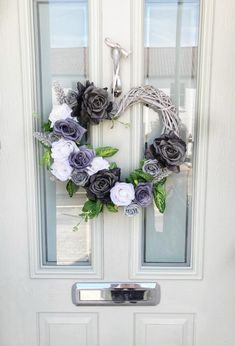 a wreath made out of fake flowers on the front door is hanging on a glass door