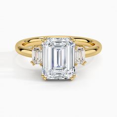 an emerald cut diamond ring with three baguets on the band and side stones