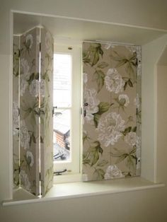 an open window in a room with floral wallpaper