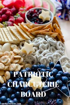 a platter filled with crackers, berries and blueberries next to other snacks