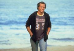 a man is standing on the beach with his hands in his pockets and smiling at the camera