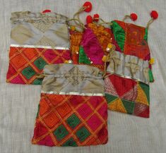 four pieces of colorful cloth with tassels and beads on them sitting on a white surface