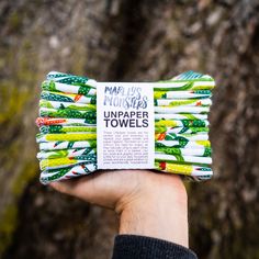 a person holding up a bundle of unpapered toothbrushes in front of a tree