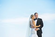 a bride and groom pose for a wedding photo on the beach in front of the ocean