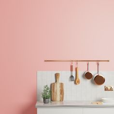 a kitchen with pink walls and wooden utensils