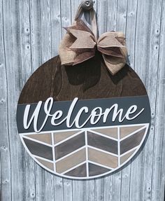 a welcome sign hanging on the side of a wooden fence with a bow attached to it