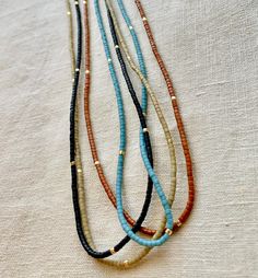 Great for everyday wear! Very tiny and delicate. Muted neutral tones. This tiny necklace is made with high quality Japanese seed beads that are perfect cylinders. Gold-filled clasp. Natural silk cord with frayed tassel ends. Available in 4 matte colors: burnt umber, palm, black, and ocean. 📏Not sure which length to choose? Add a chain extender: https://etsy.me/34lPf3m 🌎 Packaging 🌎 To be environmentally responsible about packaging we will package orders together in the same box. If certain it Everyday Gold Beaded Necklaces, Brown Beaded Necklaces With Tiny Beads, Brown Beaded Necklace With Tiny Round Beads, Adjustable Gold Beaded Everyday Necklaces, Adjustable Gold Beaded Necklaces For Everyday, Minimalist Gold Beaded Necklace For Everyday, Everyday Beaded Necklace With Round Beads, Minimalist Adjustable Beaded Necklace With Gold Beads, Adjustable Heishi Beads Necklace With Tiny Beads