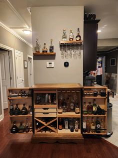 a wooden cabinet filled with lots of bottles and glasses on top of a hard wood floor