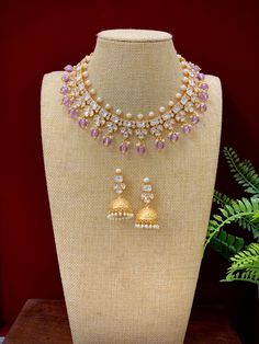 This elegant Robin tyanni kundan choker/necklace is gold-plated with tyanni kundan work and a pearl neckline. The piece is finished with lavender/lilac crystal drops and matching jhumki, all embellished with traditional kundan work. Its length is about 2 inches, with a secure push-back closure. Elegant Purple Kundan Necklace For Festive Occasions, Elegant Purple Kundan Necklace As Gift, Elegant Purple Kundan Necklace For Wedding, Elegant Purple Meenakari Jewelry, Festive Purple Kundan Necklace, Elegant Purple Wedding Choker, Festive Purple Necklace For Wedding, Purple Kundan Necklace Gift, Purple Kundan Necklace For Gifting