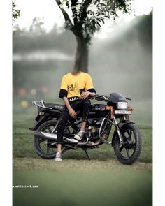 a man sitting on the back of a motorcycle in front of a tree with fog