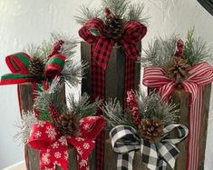 three wooden christmas decorations with pine cones and plaid bows on them, sitting next to each other