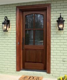 a wooden door with two lights on the side of it and a welcome mat in front of it