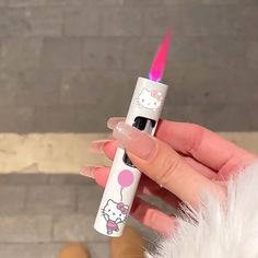 a person holding a hello kitty lighter in their right hand and wearing pink nail polish