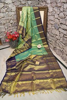 Come and buy the most elegant looking and finely-woven Tissue Kanjeevaram silk saree that has amazing golden zari work on the body, pallu and the border with traditional weaving work on the body making this saree a distinguished piece in ravishing appearance. Color: A shade of sea green and navy blue color Technique: Amazing work of golden zari traditional weaving on the whole saree Fabric: Tissue Kanjeevaram Quality: Indyvogue's Assurance of Pure Silk Mark Certified Saree Designer Paithani Silk Traditional Wear In Gold, Designer Gold Paithani Silk Traditional Wear, Gold Paithani Silk Traditional Wear, Designer Gold Handloom Lehenga, Designer Gold Paithani Silk Saree, Gold Meenakari Tissue Silk Saree, Gold Tussar Silk Saree Silk Mark Certified, Gold Raw Silk Dupatta With Silk Mark, Gold Silk Mark Certified Dupatta In Traditional Drape