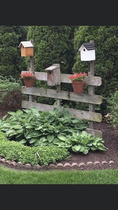 the bird house is on top of the wooden fence in the garden with plants and flowers