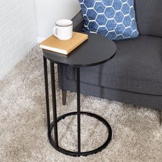 a black table with a book on it next to a gray couch and blue throw pillow