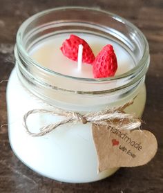 two red hearts are placed on top of a candle in a mason jar with twine