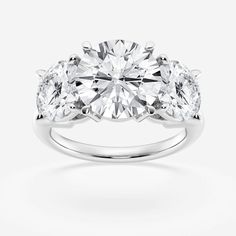 three stone engagement ring with diamonds on the sides and an oval diamond in the center