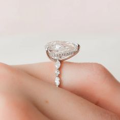 a woman's hand holding an engagement ring with a pear shaped diamond on it