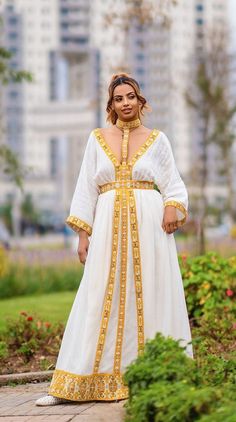 The dress is a perfect blend of traditional Ethiopian Tilef design with modern elegance, ideal for celebrations, weddings, or other significant occasions. The golden embroidery symbolizes grandeur and elevates the otherwise simple white fabric, called Menen, into a statement piece. Material Cotton Menen Thread Estimated delivery : 1week to 2weeks Contact WhatsApp +1(304)-306-2784Email: contact@ethiopian.store Ethiopia Dress, Holiday Wedding Dress, Habesha Dress, Ethiopian Dress, Golden Embroidery, Weave Fabric, Choker Style, Intricate Embroidery, Modern Dress