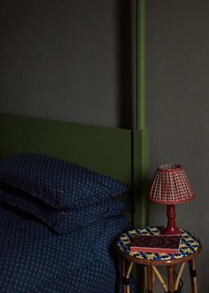 a small table with a lamp on top of it next to a blue bed sheet