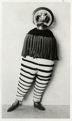 an old photo of a man in striped pants with a clock on his head and legs