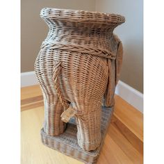 an elephant shaped wicker vase sitting on top of a wooden floor next to a wall