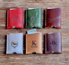 four different colored leather flasks with initials on them